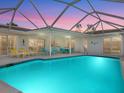 Inviting screened pool area with turquoise water, patio furniture, and a beautiful sunset at 5560 Shadow Lawn Dr, Sarasota, FL 34242