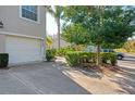 Home exterior featuring an attached garage, lush landscaping, and mature trees at 6750 Fairway Gardens Dr # 6750, Bradenton, FL 34203