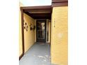 Front entrance of condo, featuring a yellow stucco exterior and a dark-colored door at 1318 56Th W St # 1318, Bradenton, FL 34209