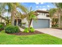 Landscaped front yard with palm trees, walkway, and a gray garage door at 19066 Mangieri St, Venice, FL 34293