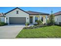 One-story house featuring a gray garage door and attractive landscaping at 209 Brindisi Cir, Nokomis, FL 34275