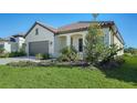 Single-story home showcasing a gray garage door and lush landscaping at 209 Brindisi Cir, Nokomis, FL 34275