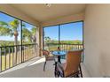 Enjoy the views of the golf course and lake on this beautiful screened in balcony with two chairs and a glass table at 7005 River Hammock Dr # 301, Bradenton, FL 34212