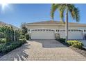 Two-car garage with paver driveway and lush landscaping at 1910 Scarlett Ave, North Port, FL 34289