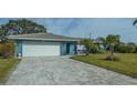 Charming blue home featuring a paved driveway, well-manicured lawn, lush landscaping, and a white garage door at 429 N Rossetti Dr, Nokomis, FL 34275