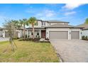 Two story house with gray siding, three car garage, and palm trees at 1012 Fernleaf Run, Bradenton, FL 34212