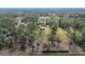 Aerial view showing a house on a spacious lot with surrounding trees and pasture at 3340 Ulman Ave, North Port, FL 34286