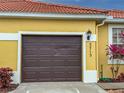 Brown garage door with house number 5715 on a yellow house at 5715 Spanish Point Ct, Palmetto, FL 34221