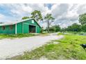 Green barn with open stall doors and gravel driveway at 1101 Anclote Blvd, Tarpon Springs, FL 34689