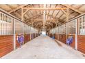 Long barn aisle with multiple horse stalls and tack at 1101 Anclote Blvd, Tarpon Springs, FL 34689