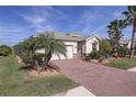 Single-story home showcasing a brick driveway, landscaping, and palm trees at 11698 Anhinga Ave, Venice, FL 34292