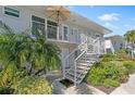 Ground level condo exterior, featuring stairs, balcony, and tropical landscaping at 521 W Venice Ave # 22, Venice, FL 34285