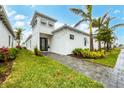 White modern house with palm trees and a landscaped yard at 6404 Pigeon Plum Way, Bradenton, FL 34210