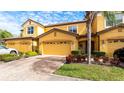Front view of a two-story townhome with yellow exterior, two-car garage, and nicely landscaped front at 8115 Miramar Way # 202, Lakewood Ranch, FL 34202
