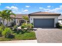 Exterior view of a single-story home with a gray garage door and landscaped yard at 14369 Eagle Branch Dr, Nokomis, FL 34275