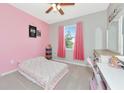 Cozy bedroom with pink accents, a comfortable bed, ceiling fan, and a window overlooking a bright exterior at 2164 Midnight Pearl Dr, Sarasota, FL 34240