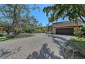 Expansive brick driveway leading to a well-maintained home surrounded by mature trees and lush landscaping at 3131 Bayou Sound, Longboat Key, FL 34228