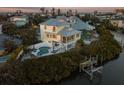 Elevated view of waterfront home, pool, and private dock at sunset at 114 Gull Dr, Anna Maria, FL 34216