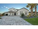 Two-story home with gray accents, paver driveway, and palm trees at 15009 18Th E Run, Parrish, FL 34219