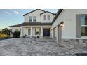 Two-story home with gray accents, paver driveway, and palm trees at 15009 18Th E Run, Parrish, FL 34219