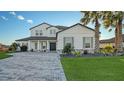 Two-story home with gray accents, paver driveway, and palm trees at 15009 18Th E Run, Parrish, FL 34219