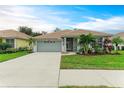 Single-story house with a two-car garage, palm trees, and well-maintained lawn at 2831 Whispering Pine Ln, North Port, FL 34287