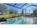 Relaxing screened-in pool with a waterfall feature and tranquil views at 7872 Mainsail Ln, Sarasota, FL 34240