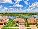 Aerial view of the home showcasing lake views, lush landscaping, and tile roof at 20686 Valprato Ct, Venice, FL 34293