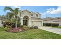 Two-story house with a green facade, arched entryway, palm trees, and landscaped yard at 4519 Trout River Xing, Ellenton, FL 34222