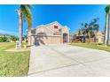 Tan house with three-car garage, red door, and palm trees at 11306 77Th E St, Parrish, FL 34219