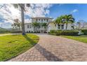 Two-story house with paver driveway, lush landscaping, and palm trees at 634 Key Royale Dr, Holmes Beach, FL 34217