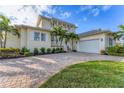 Two-story house featuring a white exterior, paver driveway, and tropical landscaping at 634 Key Royale Dr, Holmes Beach, FL 34217