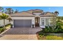 One-story home with gray garage doors, paver driveway, and lush landscaping at 10201 Beach Dune Dr, Englewood, FL 34223