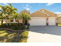 Three-car garage tan house with palm trees and manicured lawn at 14822 Trinity Fall Way, Bradenton, FL 34212