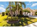 Landscaped yard with palm trees and a tan house with a three car garage at 14822 Trinity Fall Way, Bradenton, FL 34212