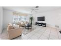 Living room with neutral colored sofas and a large TV at 1928 Greenlawn Dr, Englewood, FL 34223