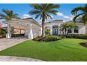 Luxury home exterior featuring a white facade, lush landscaping, and a large garage at 579 Fore Dr, Bradenton, FL 34208