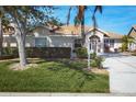 Single-story home with light tan exterior and lush landscaping at 8240 Parkside Dr, Englewood, FL 34224