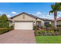 Tan house with a two-car garage, mature landscaping and a brick driveway at 11136 Shearwater Ct, Sarasota, FL 34238