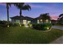 Well-lit home at dusk with lush landscaping and palm trees at 12904 49Th E Ln, Parrish, FL 34219