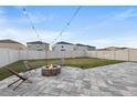 Paver patio and fenced backyard featuring a fire pit and string lights perfect for outdoor entertaining at 15304 Miller Creek Dr, Sun City Center, FL 33573