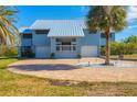 Light blue house with metal roof, two-car garage, and palm trees at 1649 Manor Rd, Englewood, FL 34223