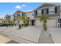 Three-unit townhome building with gray siding, two-car garages, and palm trees at 2850 Midnight Pearl Dr, Sarasota, FL 34240