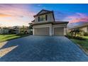 Two-story house with gray siding, tile roof, and a paved driveway at sunset at 4852 Coastal Days Ln, Bradenton, FL 34211