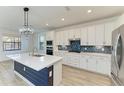 Modern kitchen with white cabinets, blue island, and stainless steel appliances at 4852 Coastal Days Ln, Bradenton, FL 34211