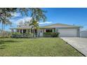 Light teal single story home with a green lawn and attached garage at 603 Barnes Pkwy, Nokomis, FL 34275