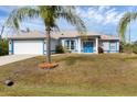 Beautiful single-story home with a two-car garage, vibrant blue trim and tropical landscaping at 2926 Sultan Ct, North Port, FL 34286