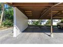 A covered carport area with a white textured wall and a view of the condo in the background at 3500 El Conquistador Pkwy # 119, Bradenton, FL 34210