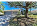 Single-story home with a two-car garage and a large oak tree in the front yard at 7215 Treymore Ct, Sarasota, FL 34243