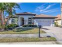 Single-story home with a white exterior, two-car garage, and manicured lawn at 129 12Th E Ave, Palmetto, FL 34221